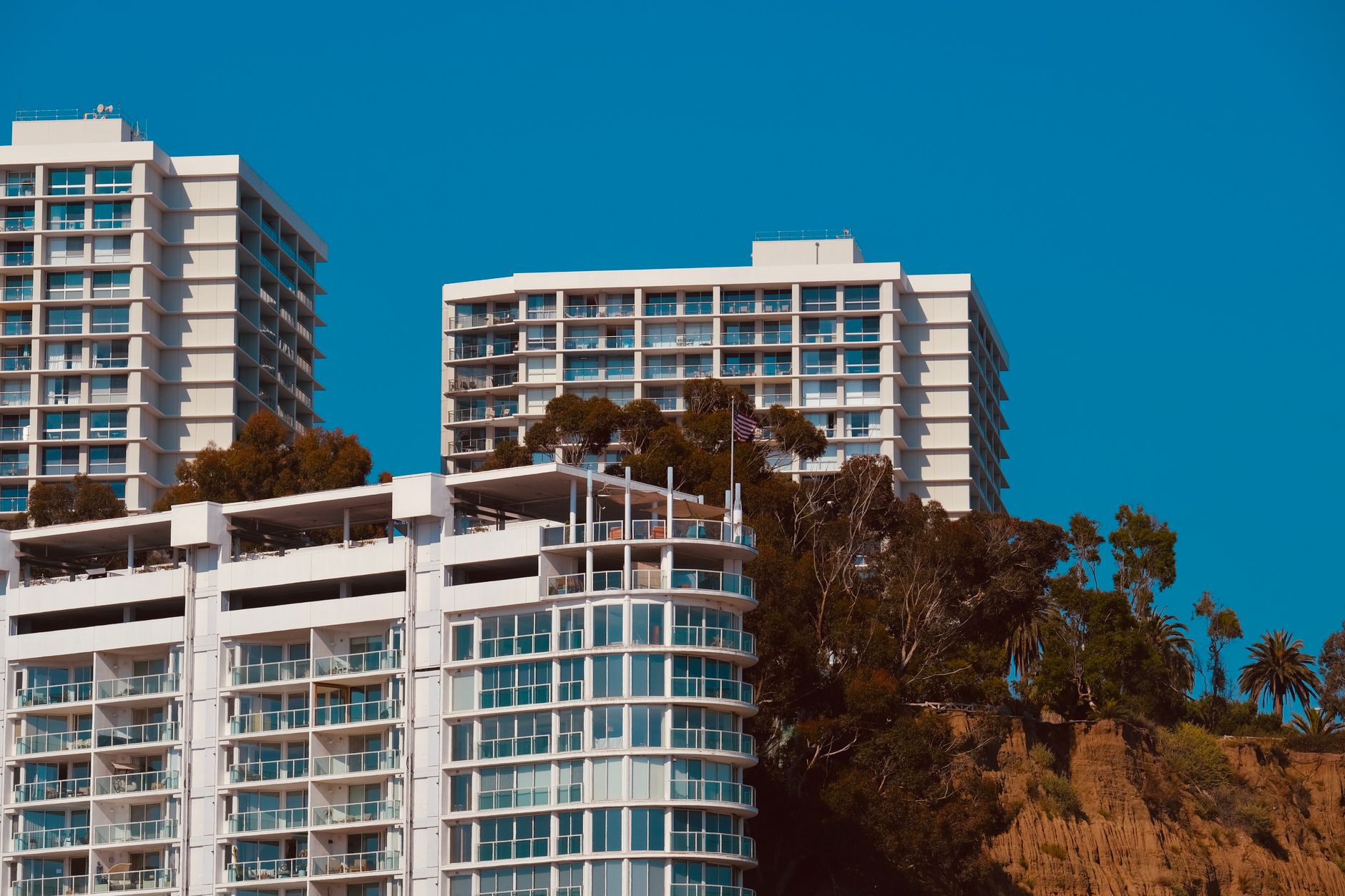 Eksterior modern Wilshire Apartments dengan balkon kaca, taman hijau, dan pencahayaan malam yang elegan