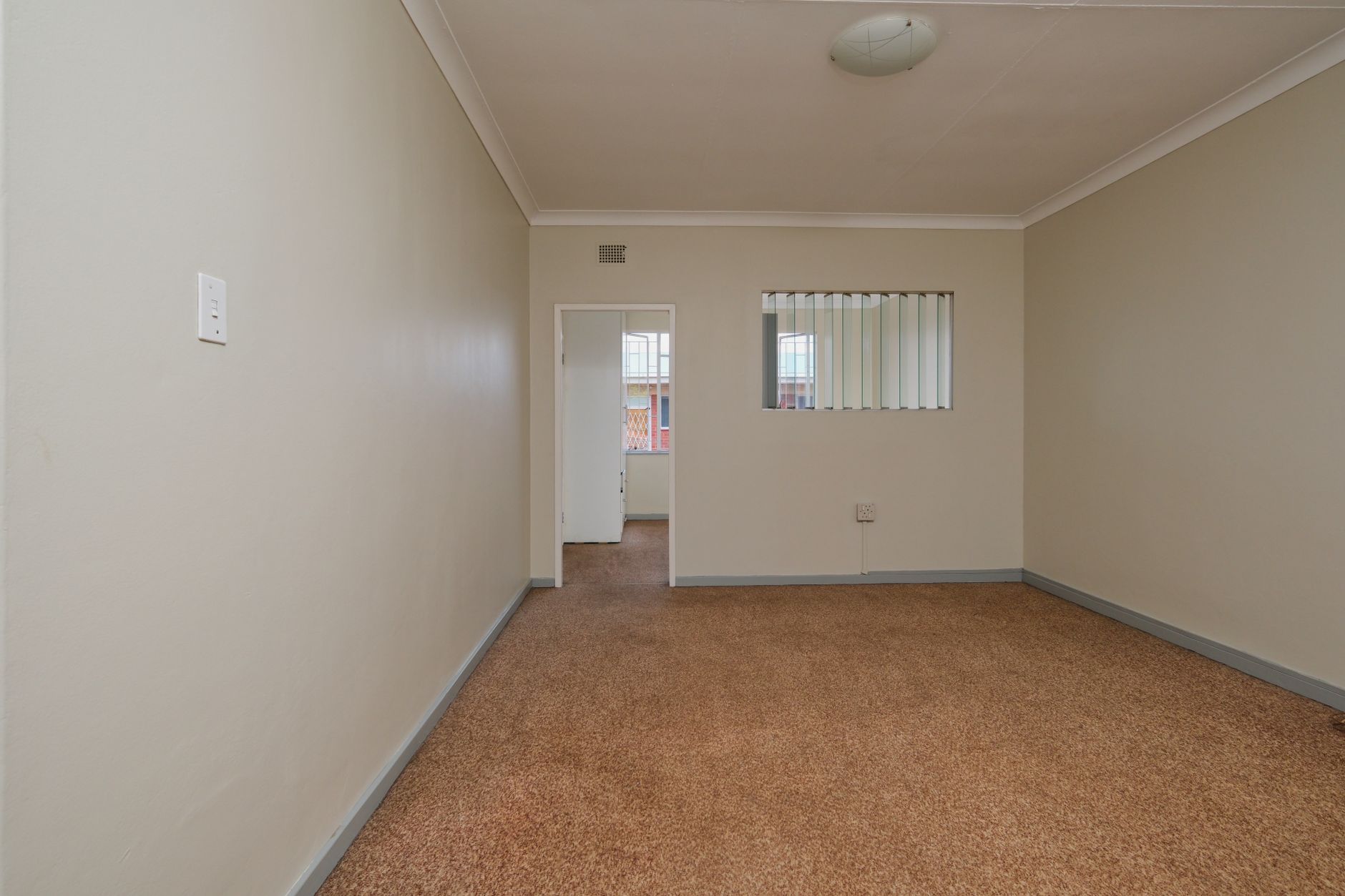 Foto interior modern flat dua kamar tidur siap disewa, menampilkan ruang tamu luas, dapur terbuka, dan pemandangan kota.
