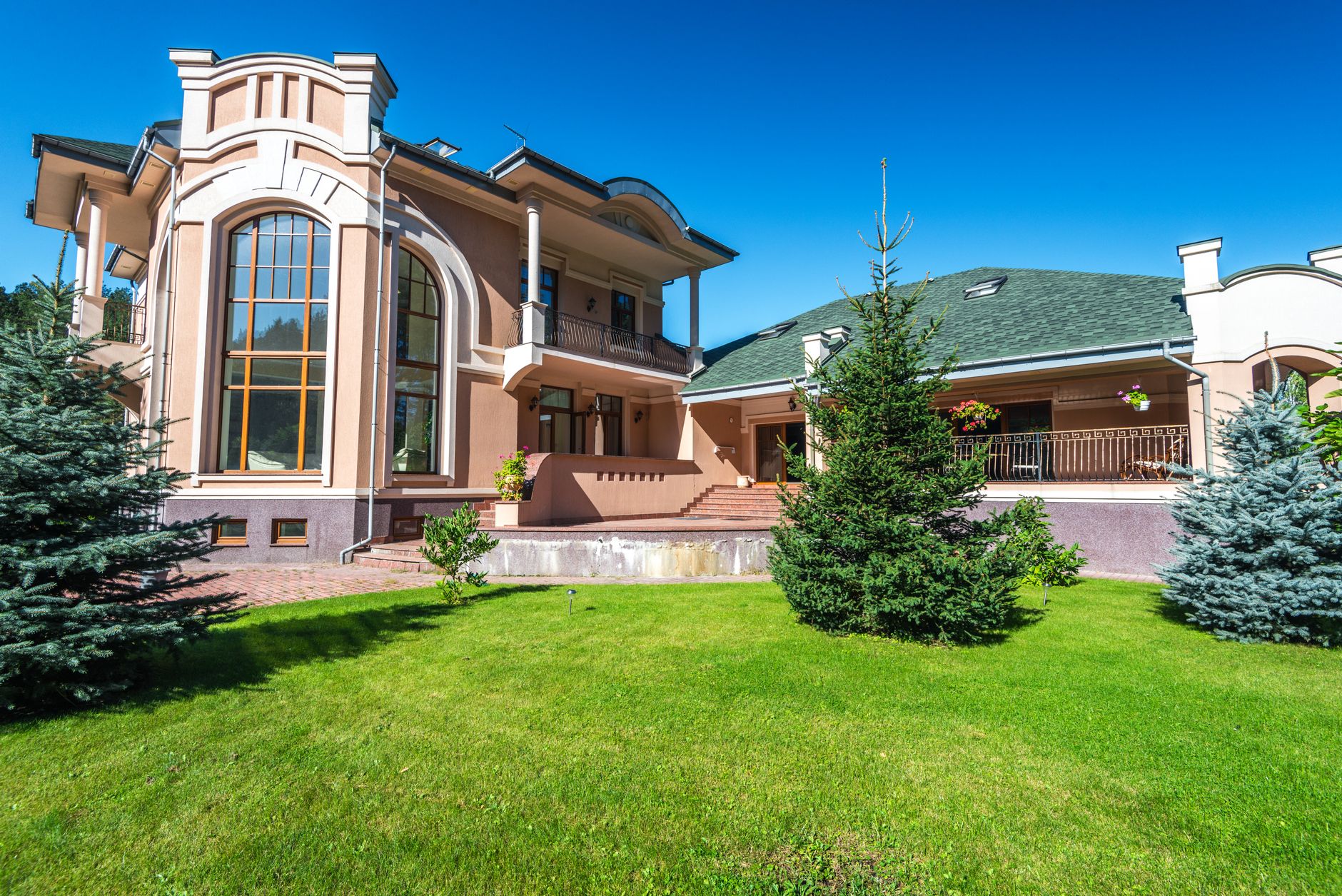 Mansion house for sale with elegant façade, large windows, and manicured garden