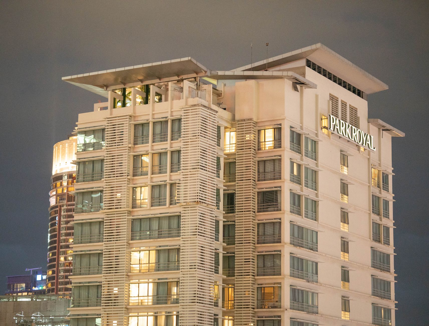 Foto eksterior modern Marc Residence dengan taman hijau dan pencahayaan malam yang elegan
